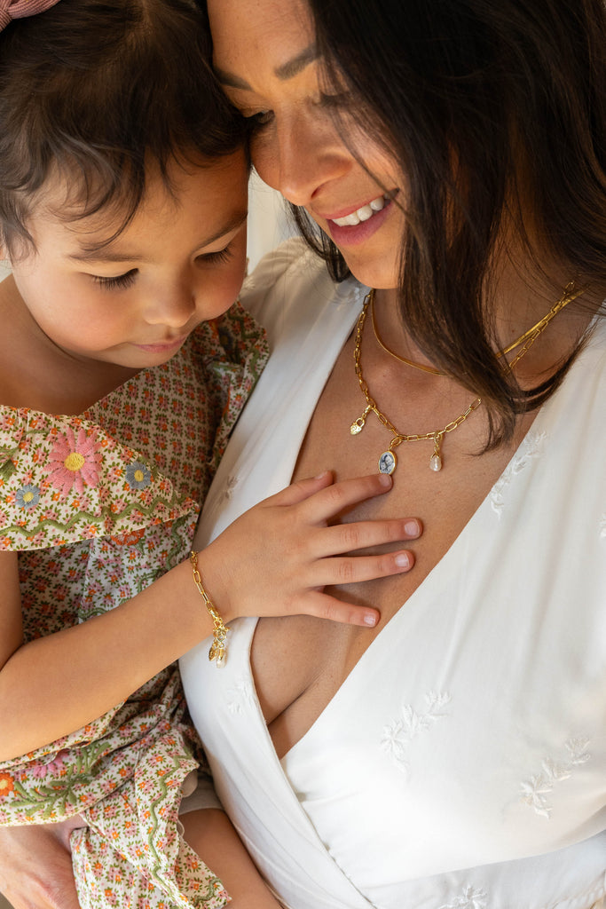 Mother Wearing Raiz Necklace and Holding Daughter