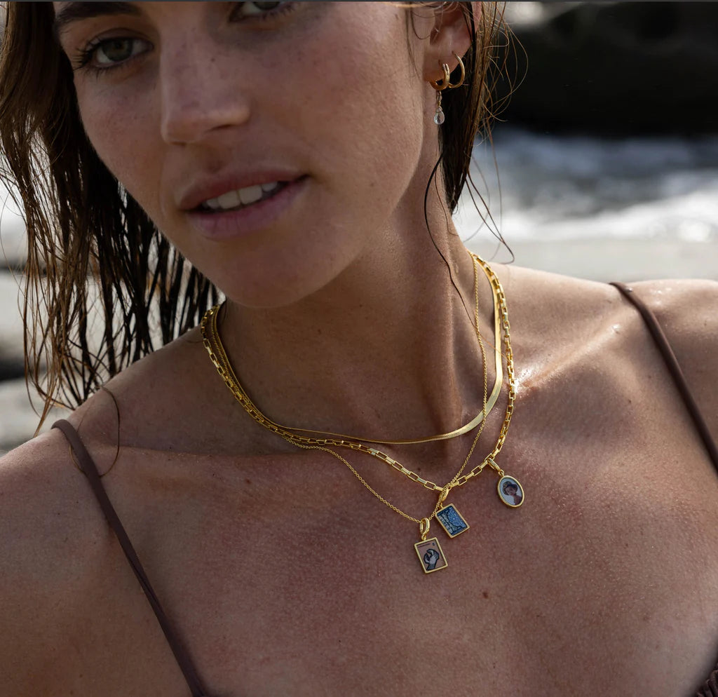 Woman wearing stacked charm necklaces with portrait and stamp charms