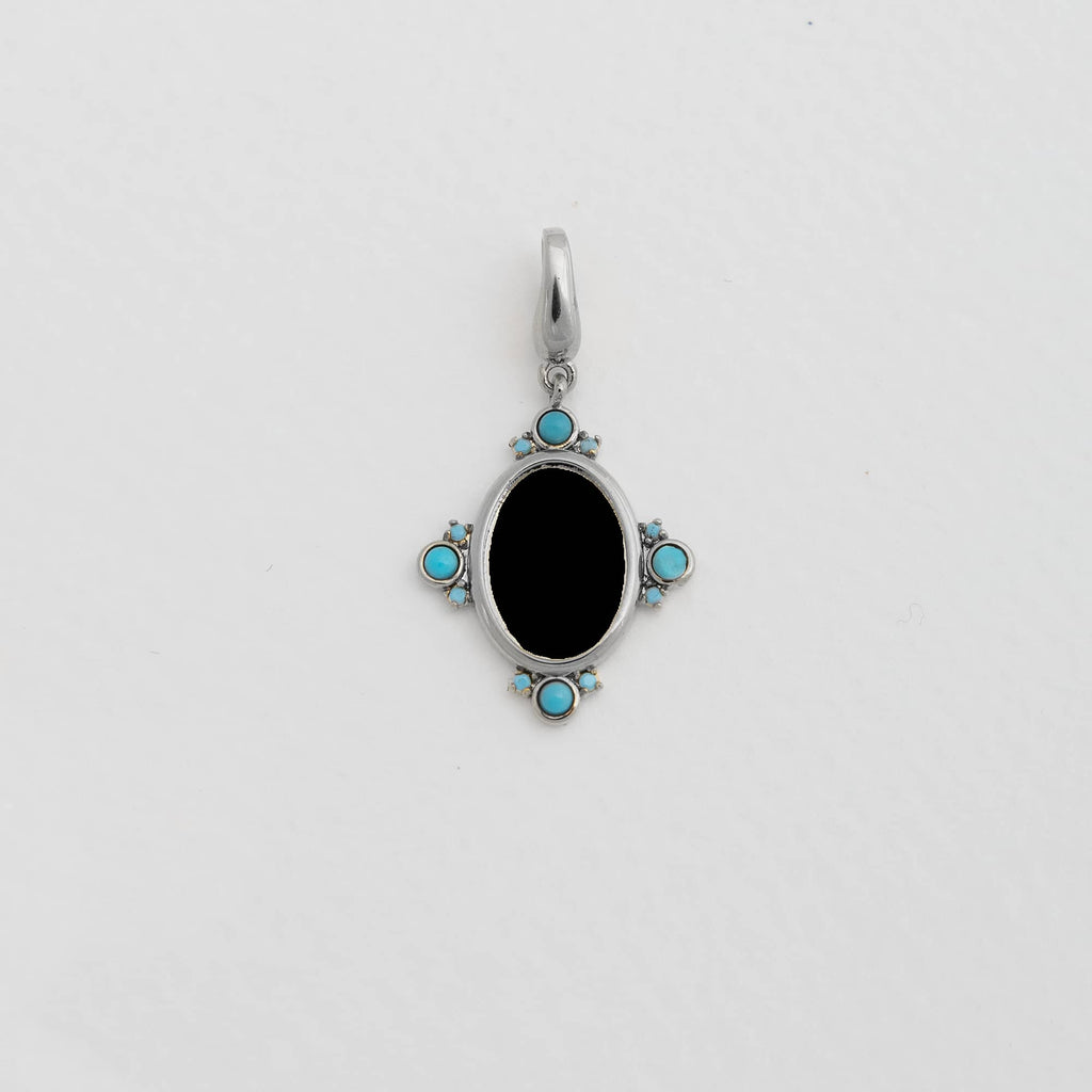 An oval silver pendant with a black center, adorned with four turquoise stones at each cardinal point.